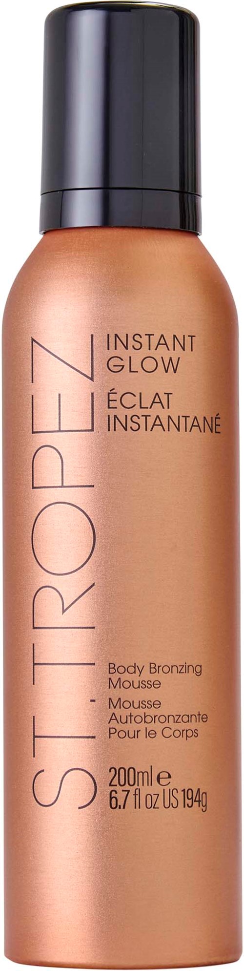 A bronze-colored spray bottle labeled 'St-Tropez Instant Glow' for body tanning, with a black cap.