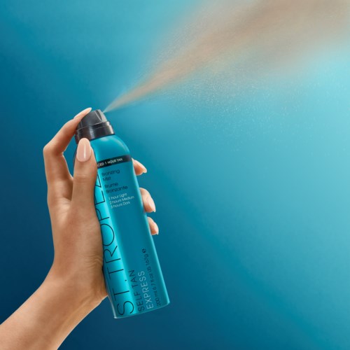Eine Hand sprüht aus einer blauen Dose Sonnenschutz gegen einen blauen Hintergrund.