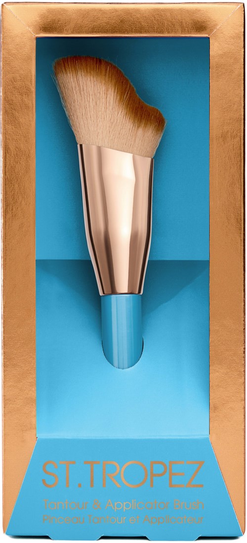 Ein Make-up-Pinsel in einer goldenen Schachtel mit blauem Hintergrund, mit der Aufschrift 'ST. TROPEZ' für Gesicht und Körper.