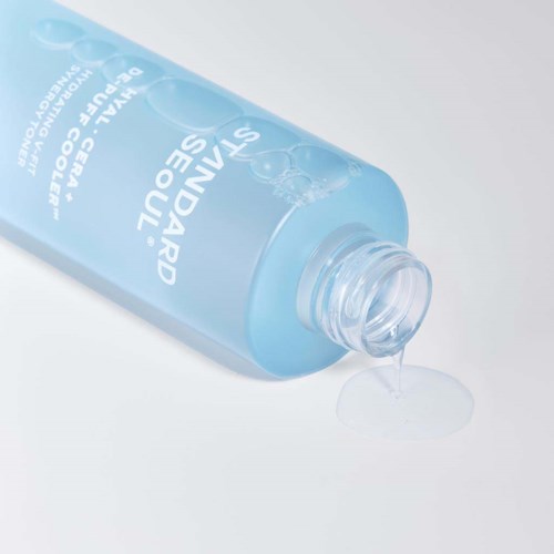 A blue bottle of cleansing water with some water pouring out and bubbles on the label.