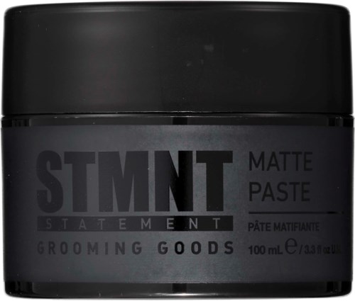 A black jar with text: "STMNT MATTE PASTE" and "GROOMING GOODS."