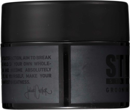 A black jar with a label that has text and a signature on it.
