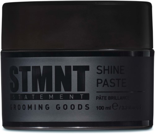 A black jar of grooming paste labeled 'STMNT SHINE PASTE' with 100 ml, dark background, bold text, and simple design.