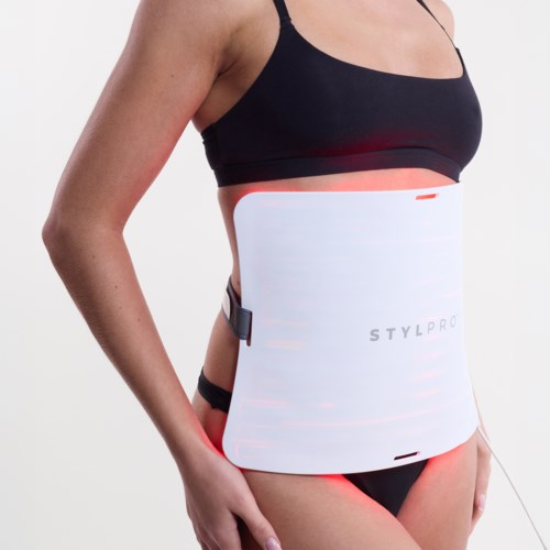 Een vrouw draagt een zwart sporttop en ondergoed, gebruikt een wit elektronisch apparaat rond haar taille voor fitness.