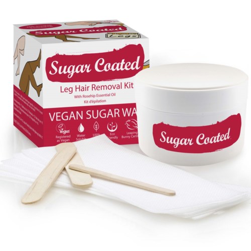 A vegan sugar wax kit with a box, jar, spatulas, and cloth for leg hair removal, using rosehip essential oil.