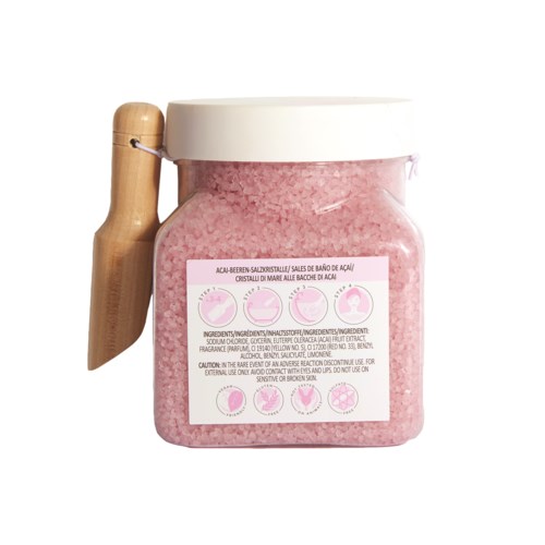 Een potje roze badzout met houten schepje en een label met productdetails en instructies.