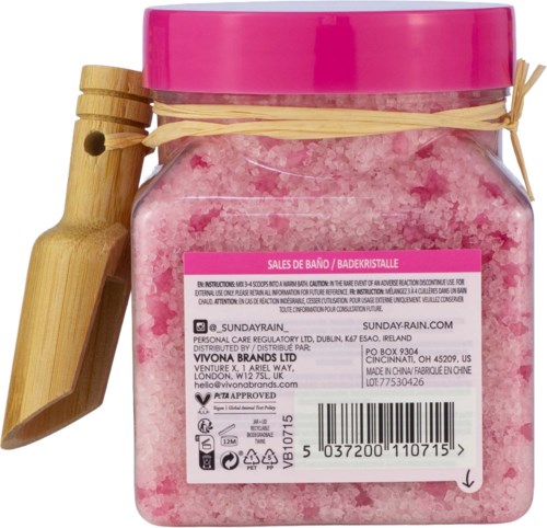 Pink badebadesalt i en klar krukke med rosa lokk og en halmlignende dekorasjon rundt.