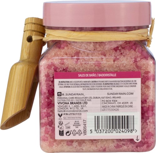 Rosa badepulver i en klar krukke med rosa lokk, bundet med en beige snor og en liten treskje festet.