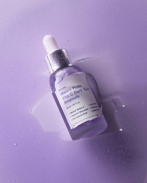 Een klein paarse fles met pipet op een paarse ondergrond, gelabeld als gezicht serum voor verheldering en donkere vlekken.