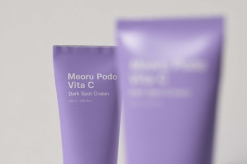 Twee paarse tubes huidverzorgingscrème, een met label 'Meoru Podo Vita C Dark Spot Cream'.
