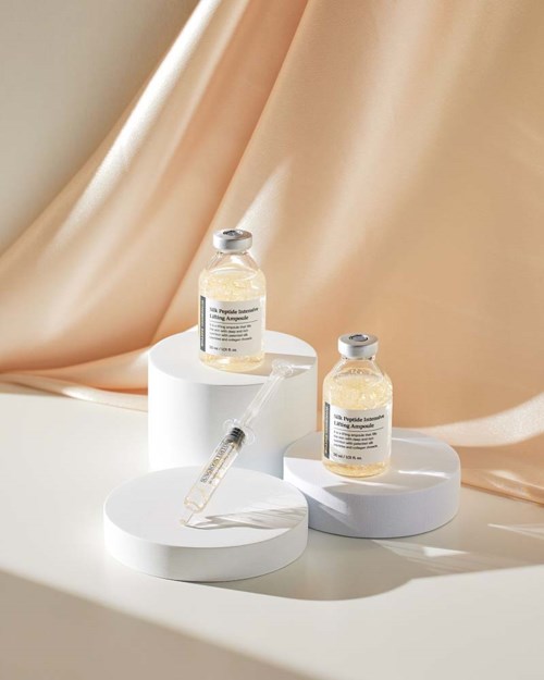 Twee medisch flessen en een spuit op witte ronde platforms met beige stofachtergrond.