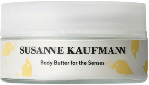 En vit burk märkt Susanne Kaufman Body Butter for the Senses med gula fiskillustrationer runt texten.