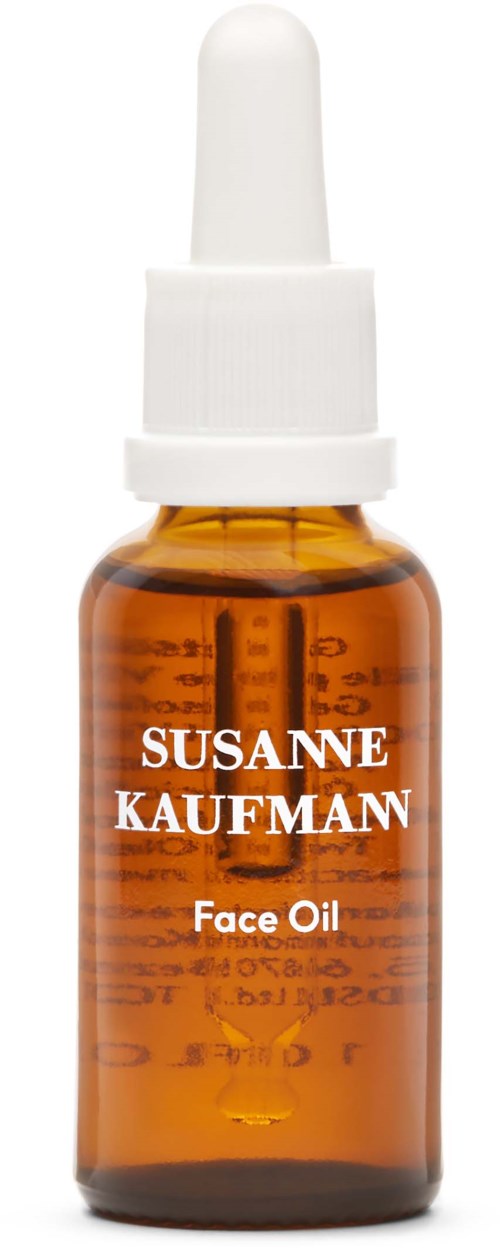 En liten bärnstensfärgad glasflaska märkt 'SUSANNE KAUFMAN Face Oil' med en vit pipettlock.