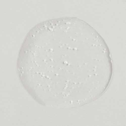 En klar, rund, geléliknande substans med små bubblor inuti på en vit yta.