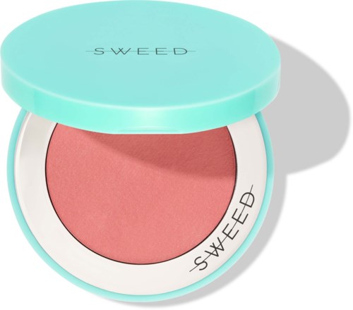 A pink blush in a round, light blue compact with a white border and black text. The lid is open.