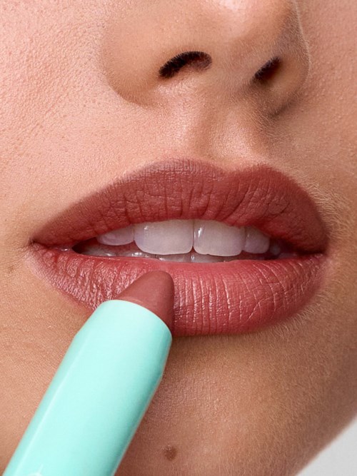 A person applying lipstick to their lips with a light blue lipstick tube.