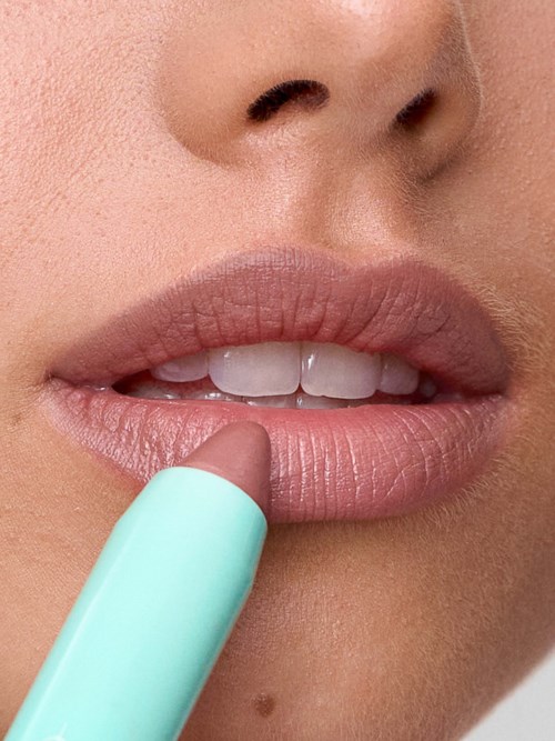 Close-up of lips and nose with a lipstick tube near the lips.