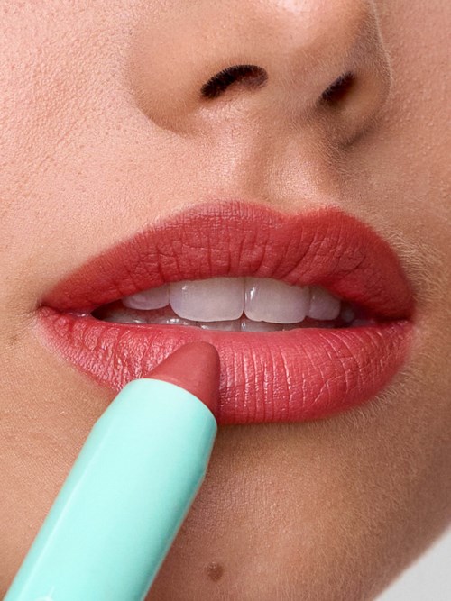 Close-up of lips being colored with lipstick, with part of the lipstick stick visible.