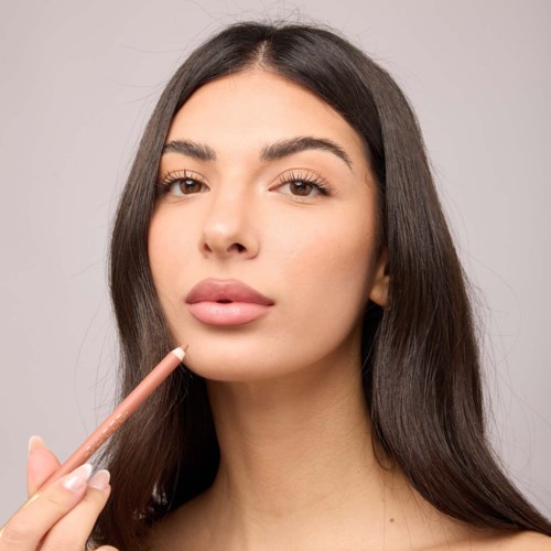 A woman with long, dark hair applying lip gloss or lipstick.