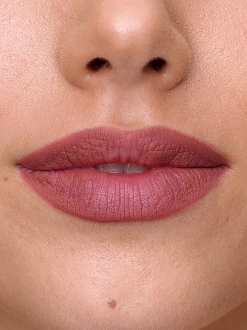 Close-up of full lips with smooth skin and a small beauty mark below.
