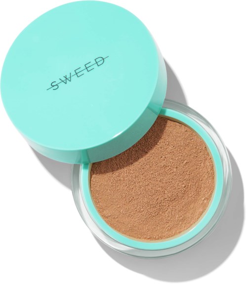 A round, teal container labeled 'SWEED' holds brown makeup powder. The lid is open, showing the powder inside.
