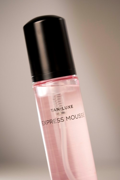 A clear pink bottle with black cap, labeled 'TAN-LUXE EXPRESS MOUSSE'.