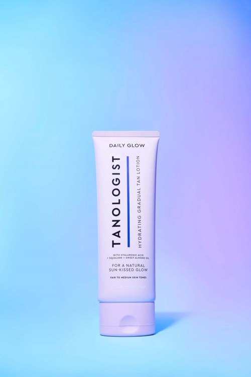 Biała tubka lotiony Tanologist Daily Glow stoi na tle gradientu od niebieskiego do fioletowego.