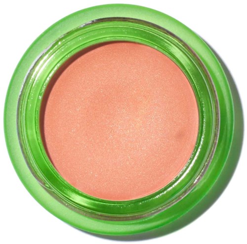 A peach-colored makeup blush in a round, green container with a shiny surface.