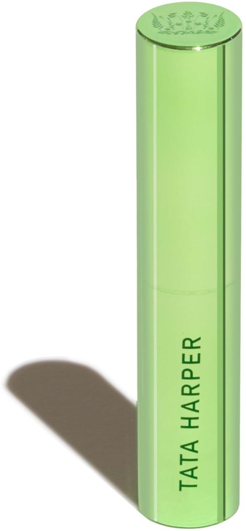 A green cylindrical object with the words "TATA HARPER" written vertically on it, casting a shadow.