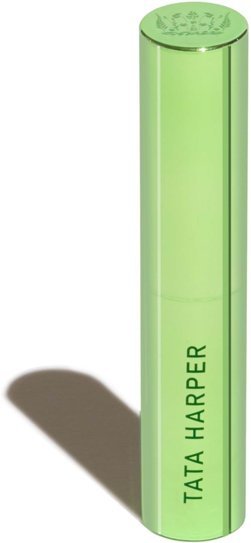 Green cylindrical object with 'TATA HARPER' written vertically on it. Casting a shadow to the left. Likely a cosmetic product.
