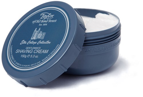A blue round container of Taylor shaving cream, with lid slightly open showing white foam inside.