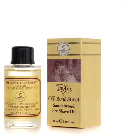 A small bottle of sandalwood pre-shave oil next to its yellow box with text and logo.