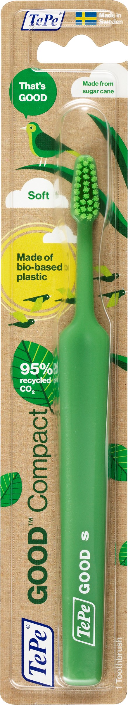 Green toothbrush with soft bristles, eco-friendly, compact design, on wooden background with green leaves.