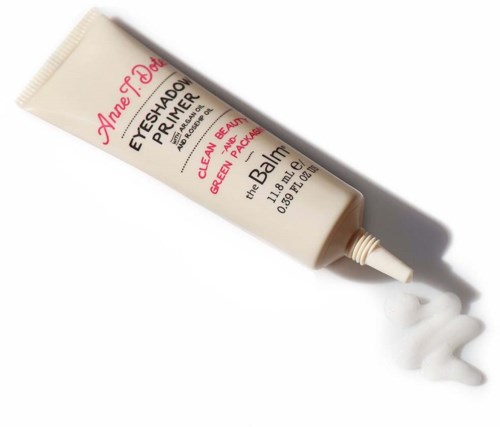 Een tube oogschaduw-priming met witte crème die eruit komt, gelabeld voor groen en perzik kleuren.