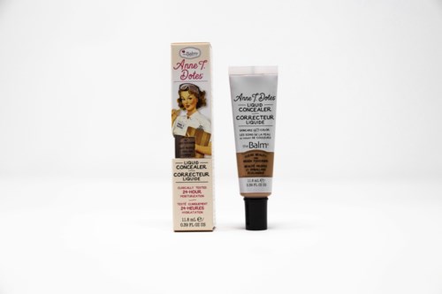 Een kleine tube concealer met vintage-style verpakking en een bijpassende doos, gemerkt 'Annette Dotes' en 'Liquid Concealer'.