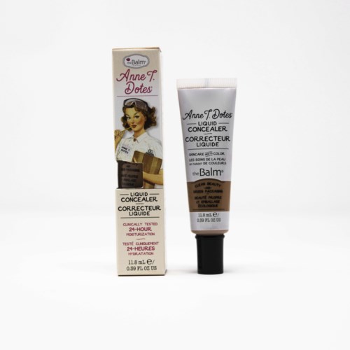 Een tube en doos van theBalm Anne T Dotes vloeibare concealer met vintage vrouwillustratie. De doos toont productgegevens en merk.