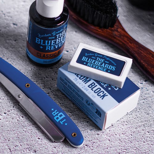 Safety razor, shaving soap, and brush on textured surface.