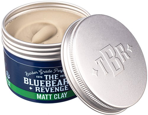 A metal container with blue and green label, open showing beige clay inside, and a closed lid with embossed 'TBBR'.