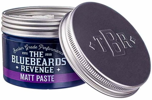 A round metal tin with a purple and black label, containing hair styling paste called "The Bluebeards Revenge Matt Paste."