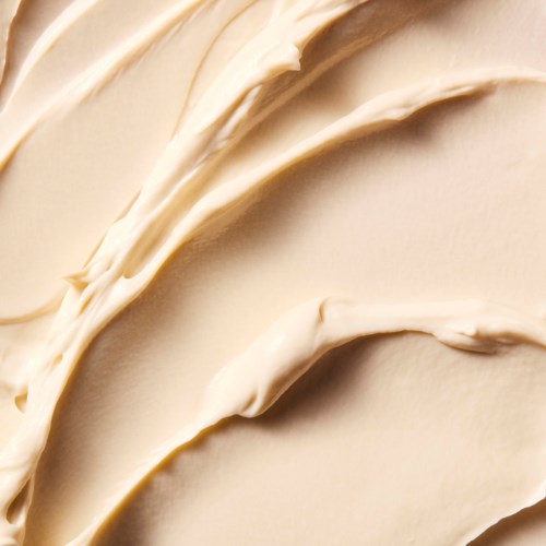 Cremiger, glatter Zuckerguss mit dekorativen Schwüngen und Linien auf einer Kuchenoberfläche.