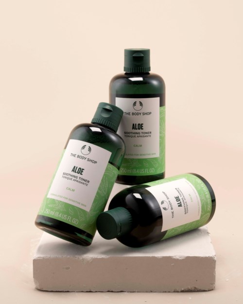 Three bottles of Aloe soothing toner and one bottle of Aloe soothing facial wash on a white platform.
