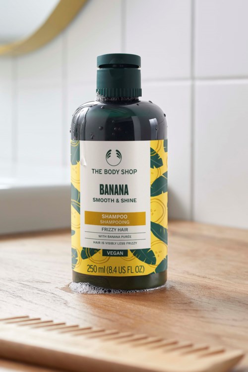 Eine Flasche Bananen-Shampoo für glattes, glänzendes, krauses Haar mit grünem und gelbem Etikett und schwarzem Deckel.