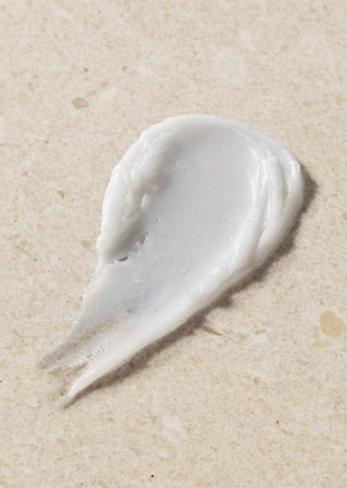 Ein Klecks weiße Creme auf einer beigen Oberfläche.