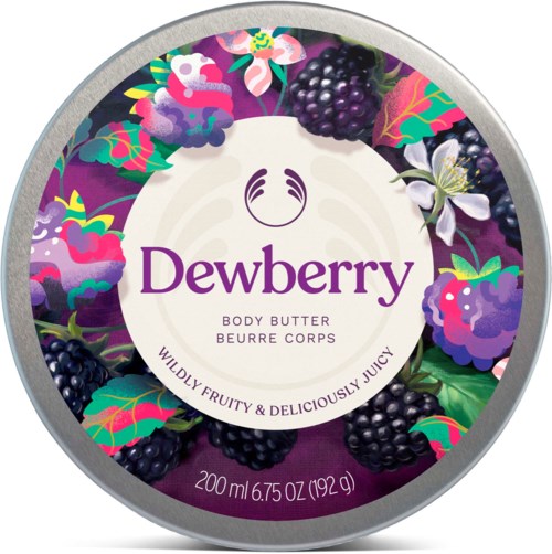 En rund beholder med Dewberry kroppssmør omgitt av bjørnebær og fargerike blader, med lilla og hvite blomsterdekorasjoner.
