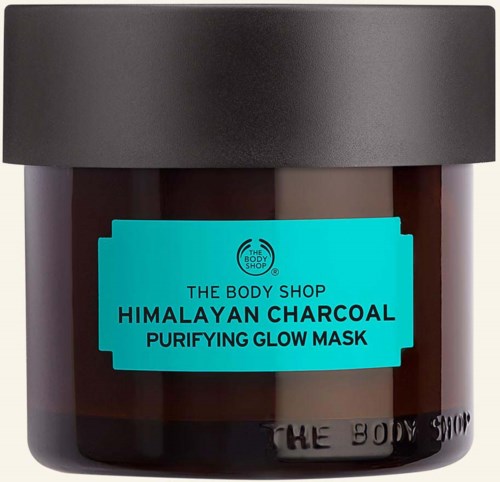 En brun burk med svart lock har en ljusblå etikett som säger: The Body Shop Himalayan Charcoal Purifying Glow Mask.