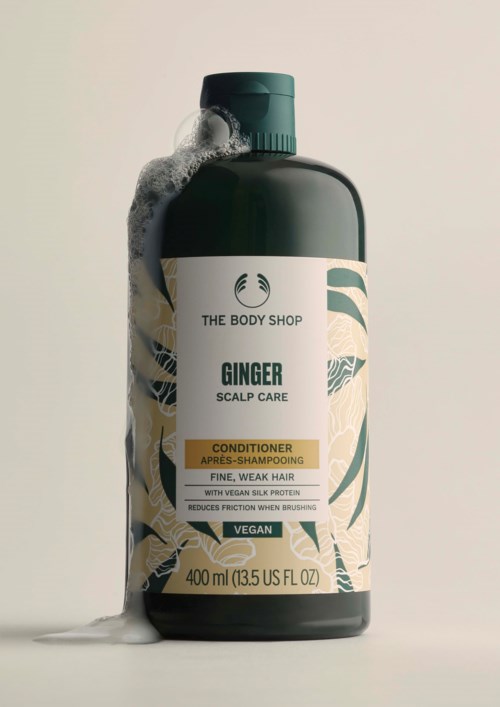 Eine Flasche Ingwer-Kopfhautpflegeconditioner von The Body Shop mit Schaum auf der Oberseite, enthält 400 ml.