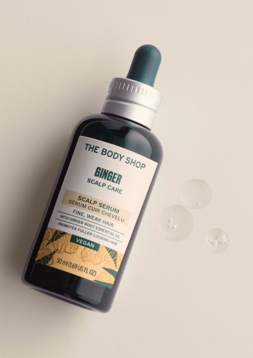 Ingwer-Scalpsserum von The Body Shop mit Pipette und einige Serumtröpfchen auf weißer Oberfläche.