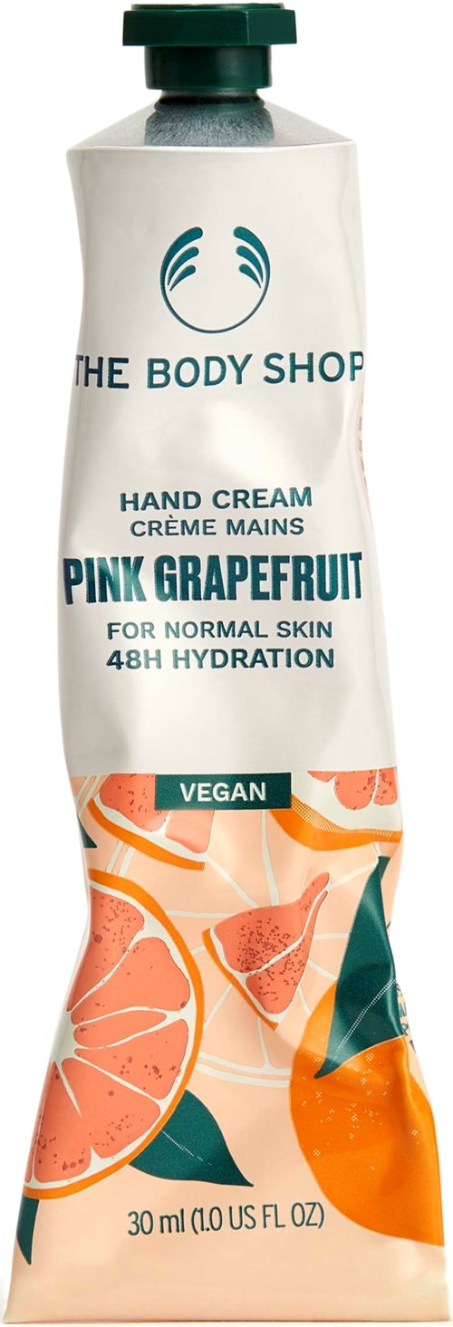 A tube of hand cream with a green cap, labeled 'The Body Shop,' features pink grapefruit illustrations and is marked vegan.