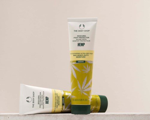 To tuber av The Body Shop hemp fotbeskyttelse, en står opp og en ligger, med grønne lokk og gule etiketter.