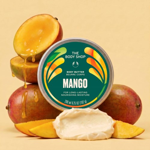 En burk mango-doftande kroppssmörj med hela och skivade mango och lite smält mangojuice.